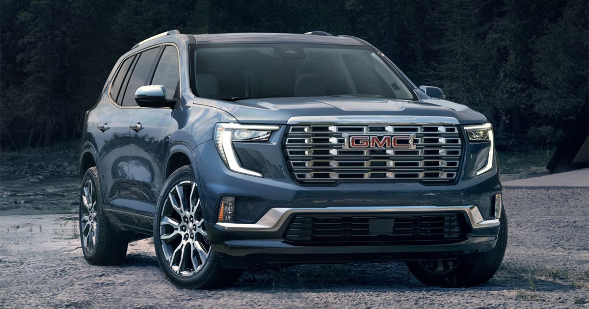 Blue 2025 GMC Acadia mid-size SUV with distinctive LED headlights and bold front grille design