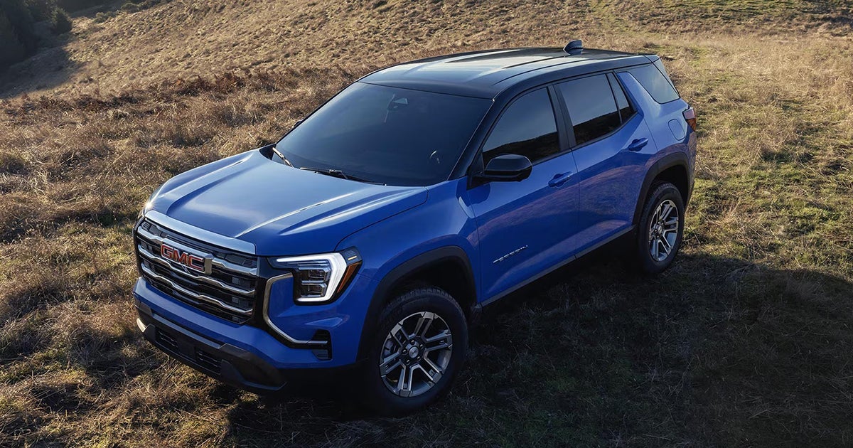 Blue 2026 GMC Terrain compact crossover SUV positioned in natural hillside setting
