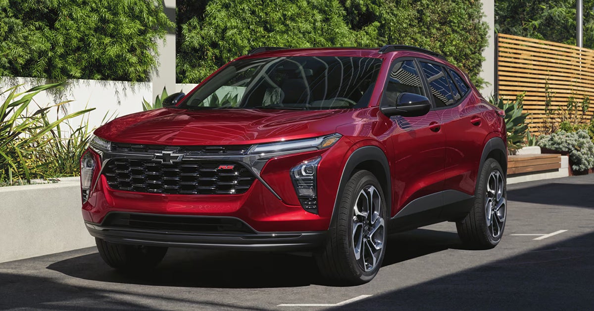 Red 2025 Chevrolet Trax RS with black accents parked in modern residential driveway