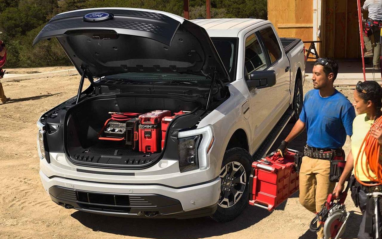 Ford F-150 Lightning work truck with people beside it.