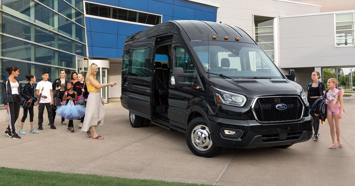 2025 Ford Transit van in black parked outside a modern building, used for group transportation, available at South Bay Ford near Los Angeles, CA.