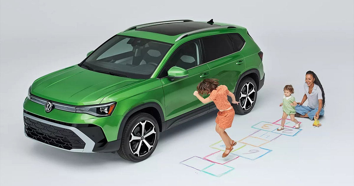 Green Volkswagen SUV with family playing hopscotch, showcasing family-friendly design and active lifestyle appeal