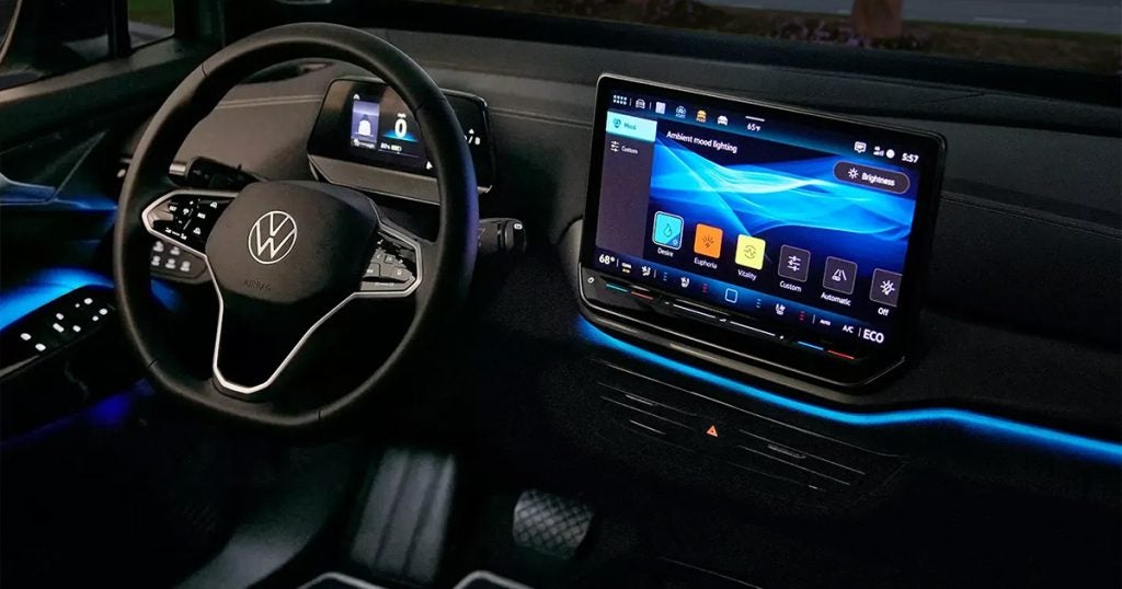 Volkswagen electric vehicle interior with digital dashboard, ambient lighting, and large touchscreen display showing climate controls