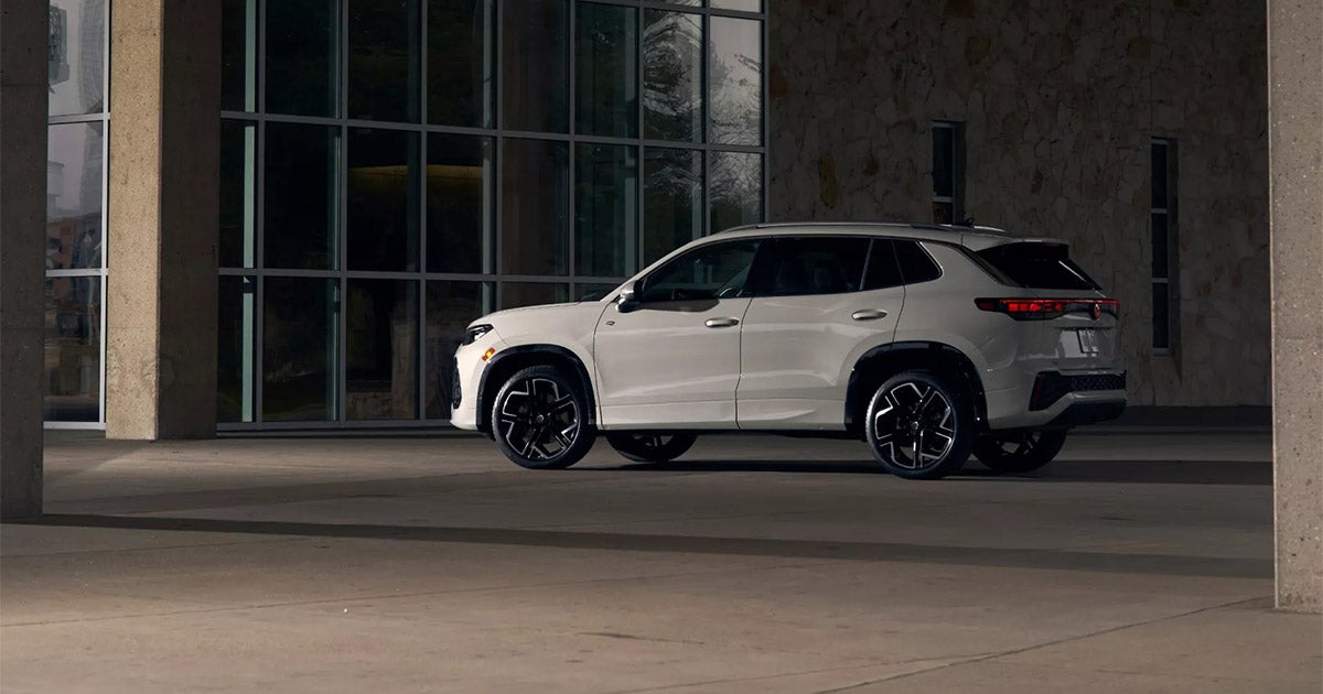White Volkswagen SUV (likely Touareg) parked in modern glass-windowed building with sleek black wheels