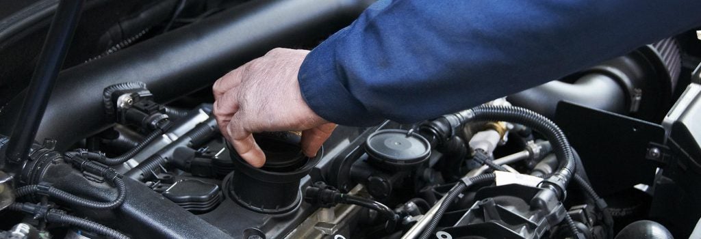 A Maintenance professional is making adjustments in a GMC SUV engine