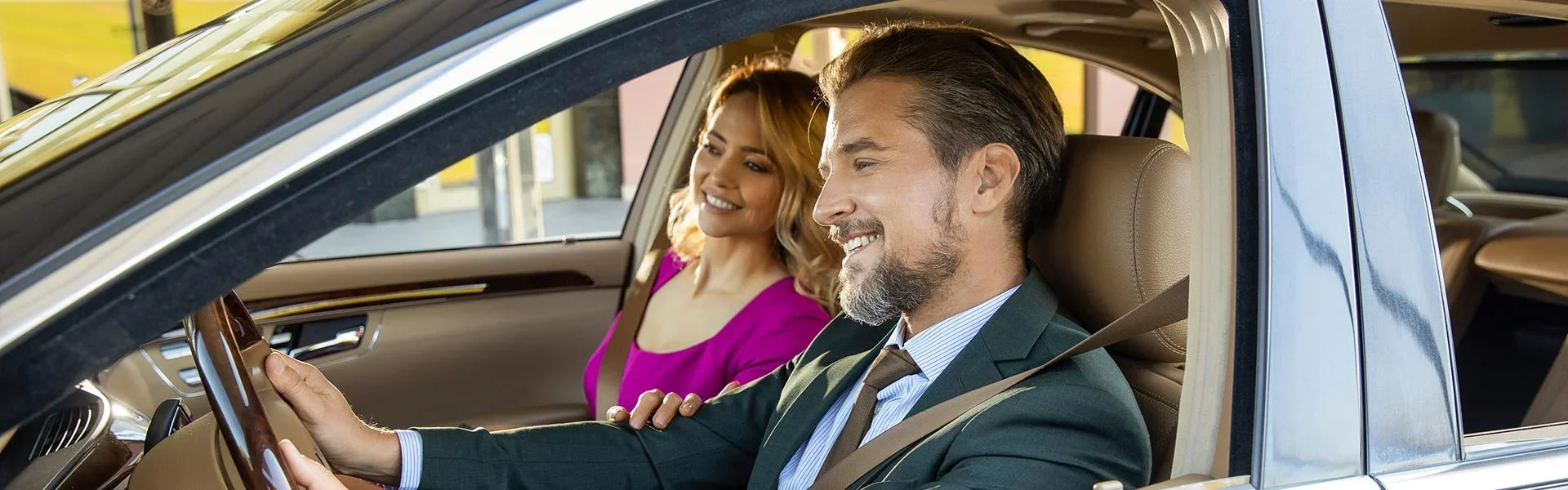 A smiling couple are enjoying driving an SUV