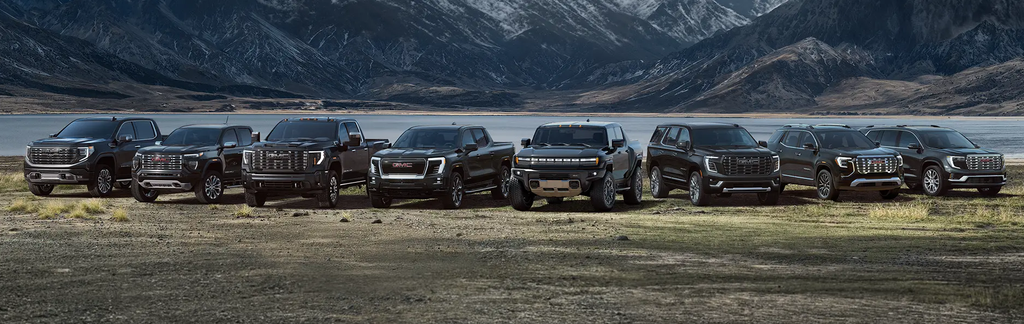GMC truck and SUV lineup displayed in a scenic mountain landscape.