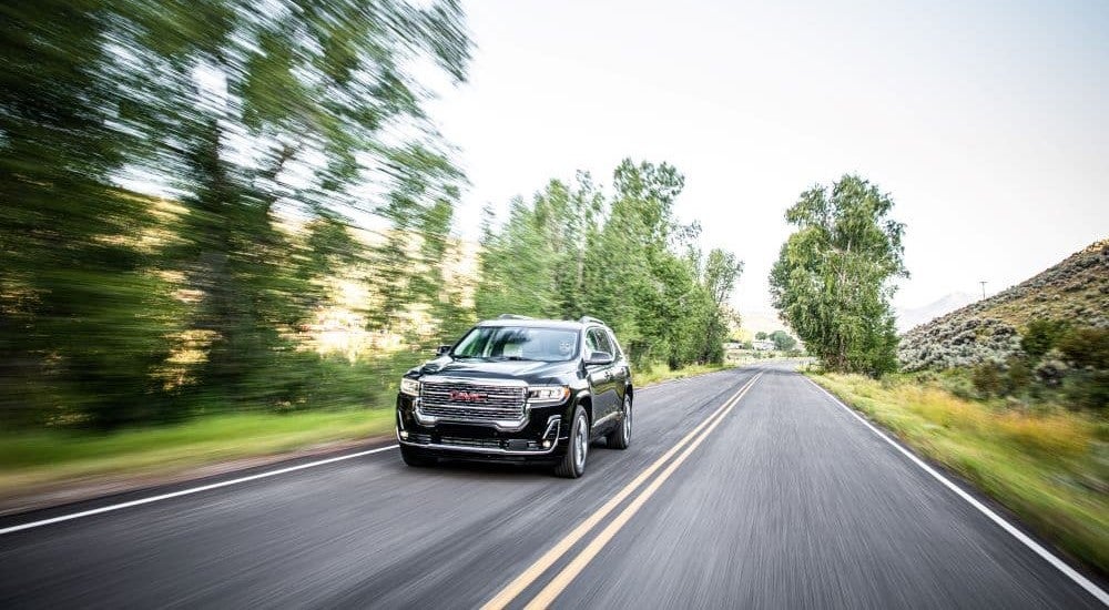Black 2020 GMC Acadia Denali driving on a highway