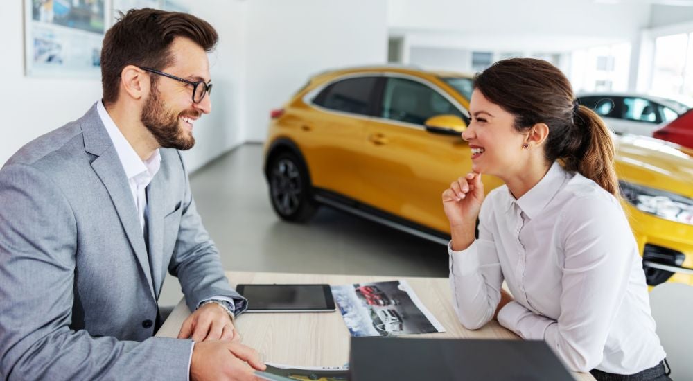 A car salesman is shown speaking to a customer on how to value their trade.