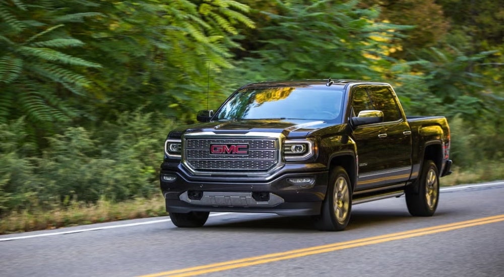 A black 2016 GMC Sierra 1500 Denali driving to a used GM dealership.