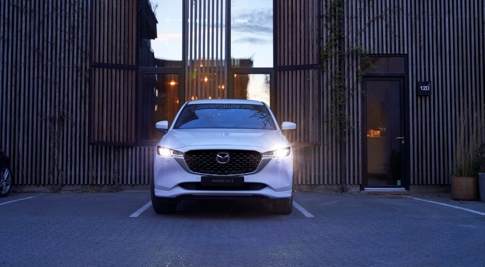 A white 2022 Mazda CX-5 is shown parked in front of a building.