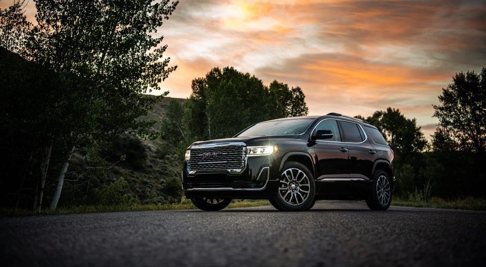 A black 2020 GMC Acadia Denali is shown parked on pavement at sunset