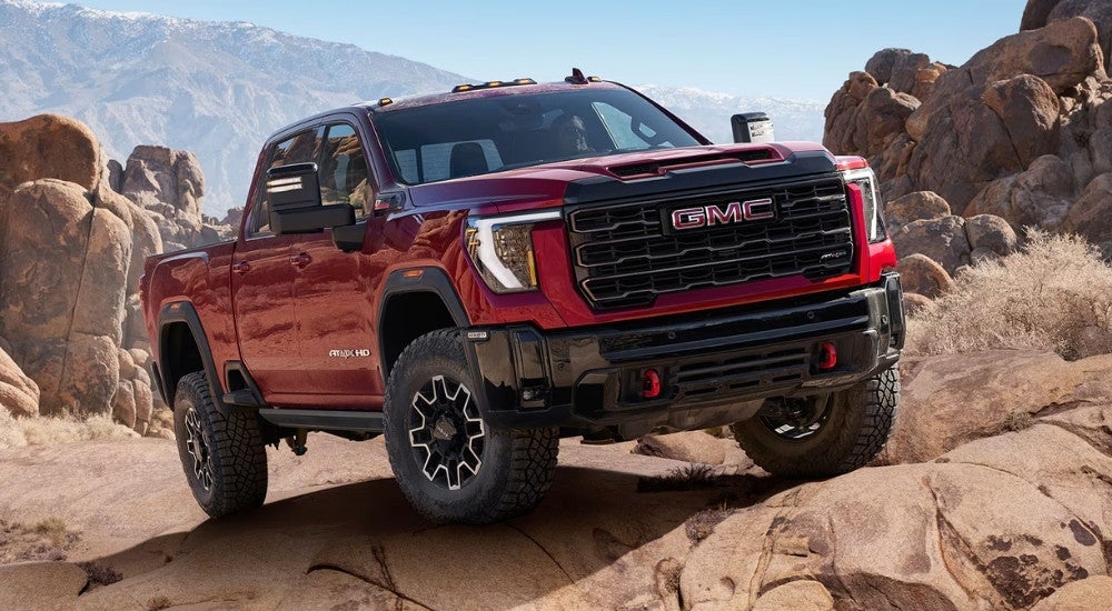 Red 2024 GMC Sierra 2500 HD driving through a desert.