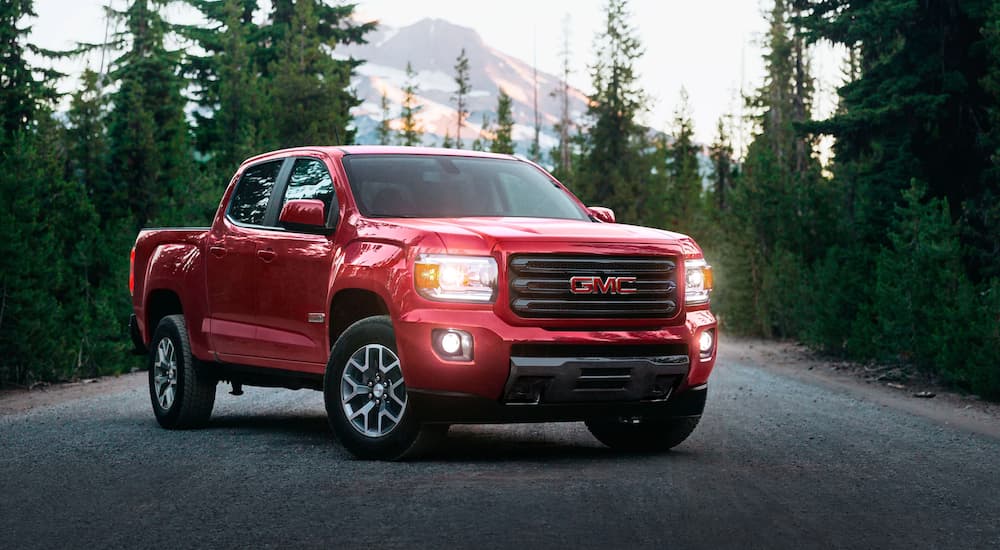 A red 2020 GMC Canyon is shown parked in the center of a forest road.