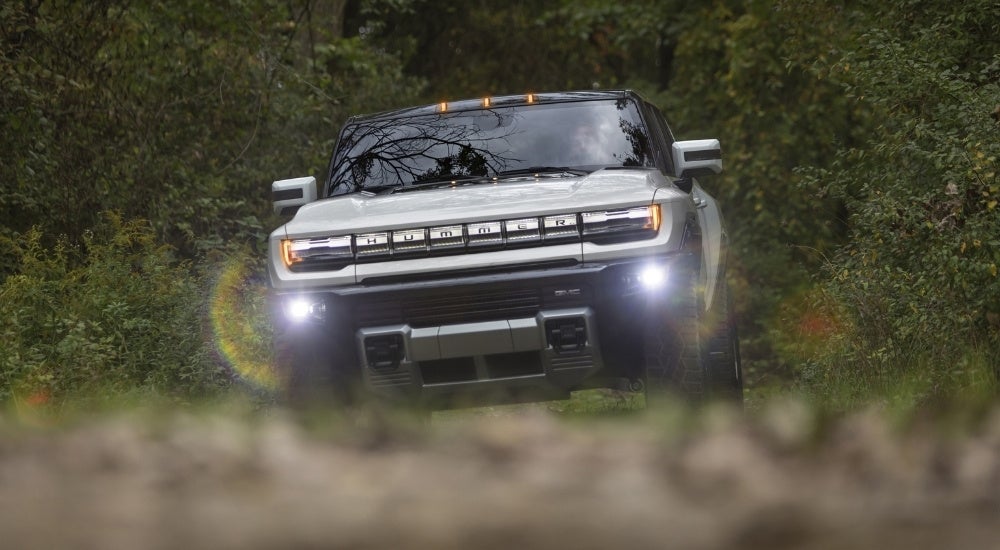A white 2025 GMC Hummer EV is shown driving to a GMC dealer near Iuka.