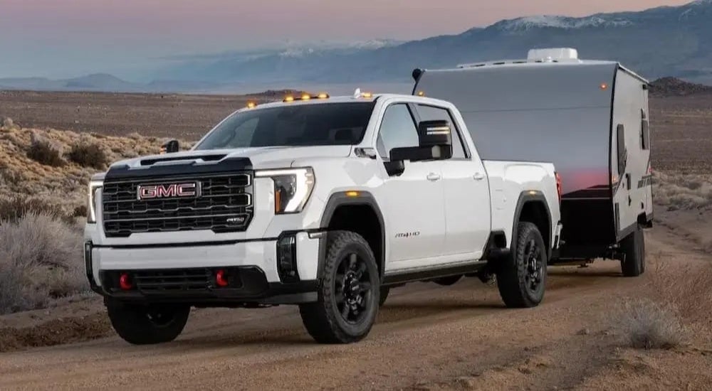 A white 2024 GMC Sierra 3500 AT4 is shown towing a trailer.