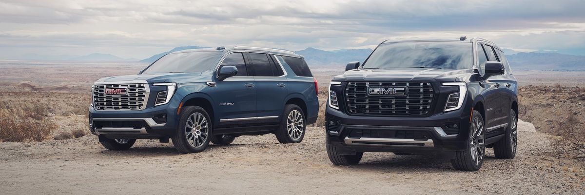 Two 2026 GMC Yukon Denali SUVs parked on a scenic overlook, front three-quarter view
