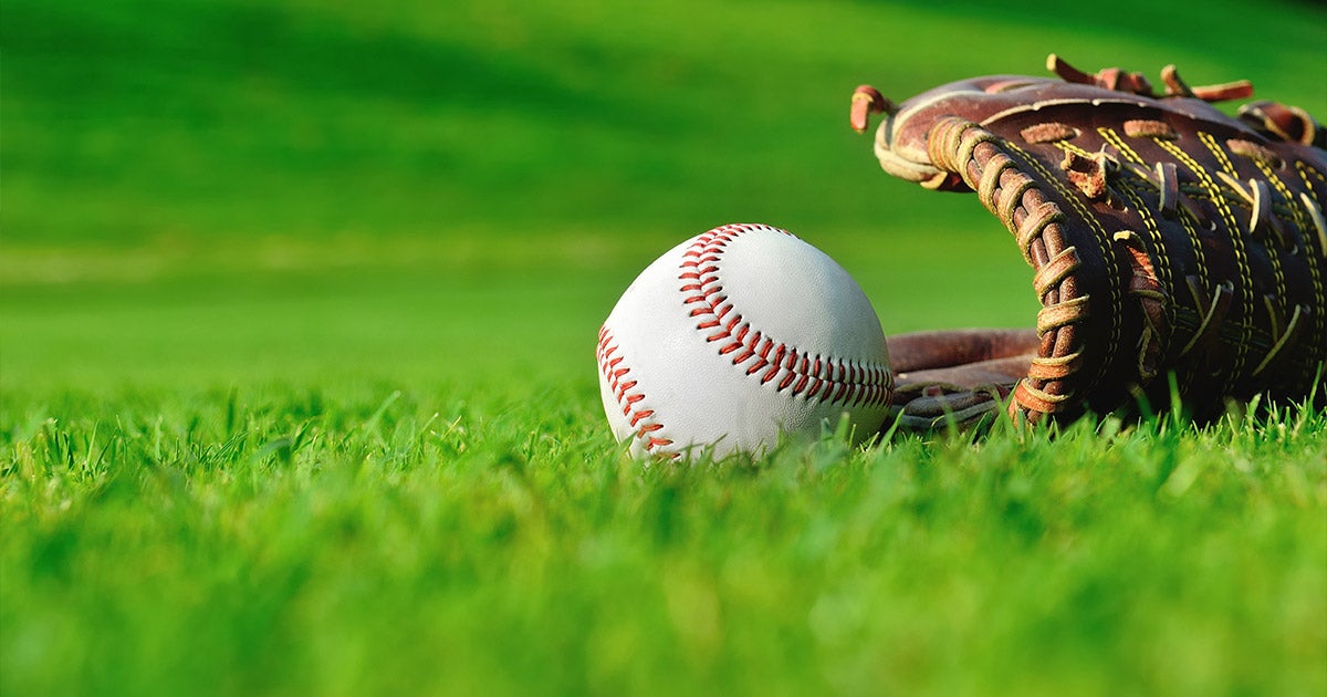 A baseball and a baseball glove laying on green grass.