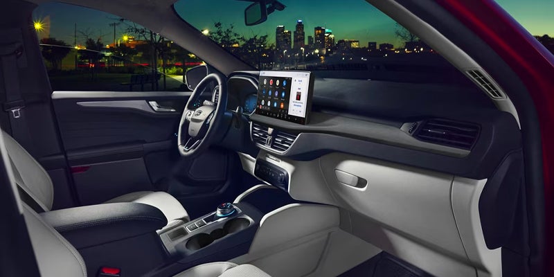 View of a car's interior from the passenger side, with a central touchscreen and city lights visible outside.