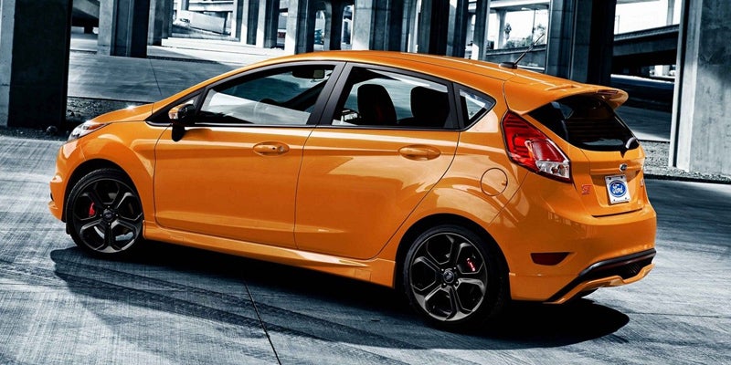 Orange Ford Fiesta parked on concrete, seen from a high angle at the rear-side, with tire marks on the ground.