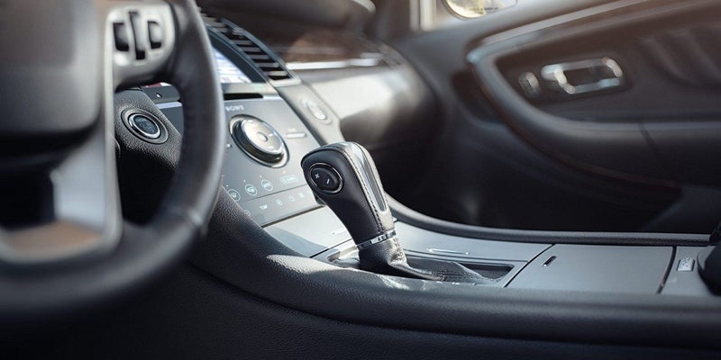 Interior of a modern car, showing the automatic gear shift, dashboard with touch screen, and steering wheel.