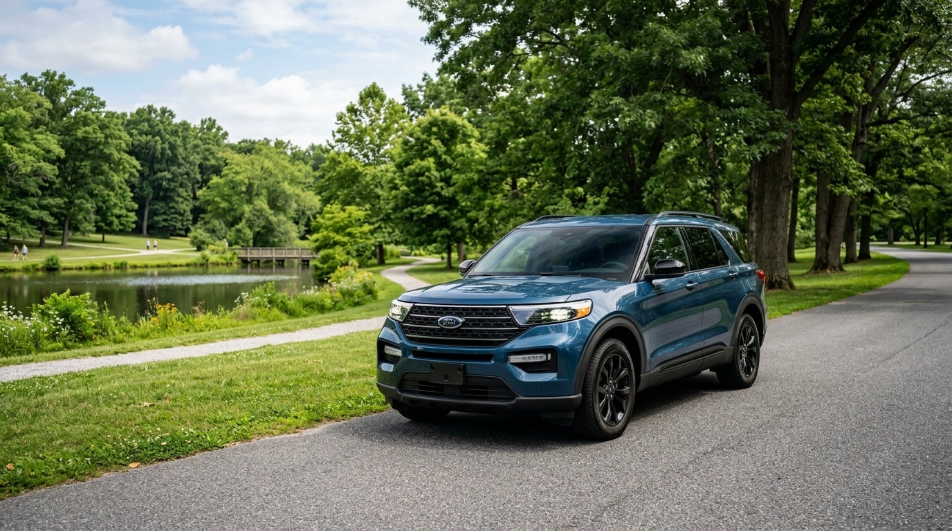 A blue Ford Explorer SUV parked on a paved road next to a grassy park with a lake and trees. (Representative image for illustration purposes only. Actual vehicle may vary based on trim and configuration.)