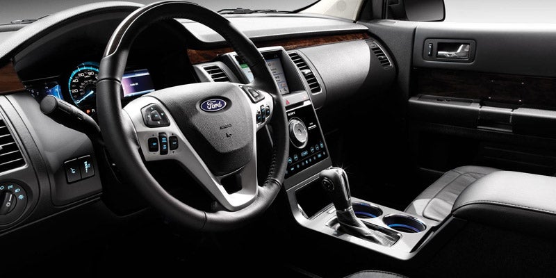 Interior shot of a car dashboard and steering wheel, showing infotainment screen and controls.