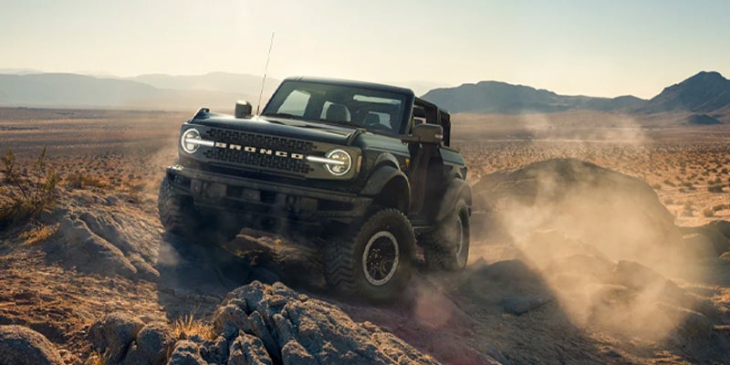 Off‑road Ford Bronco driving over rocky desert terrain