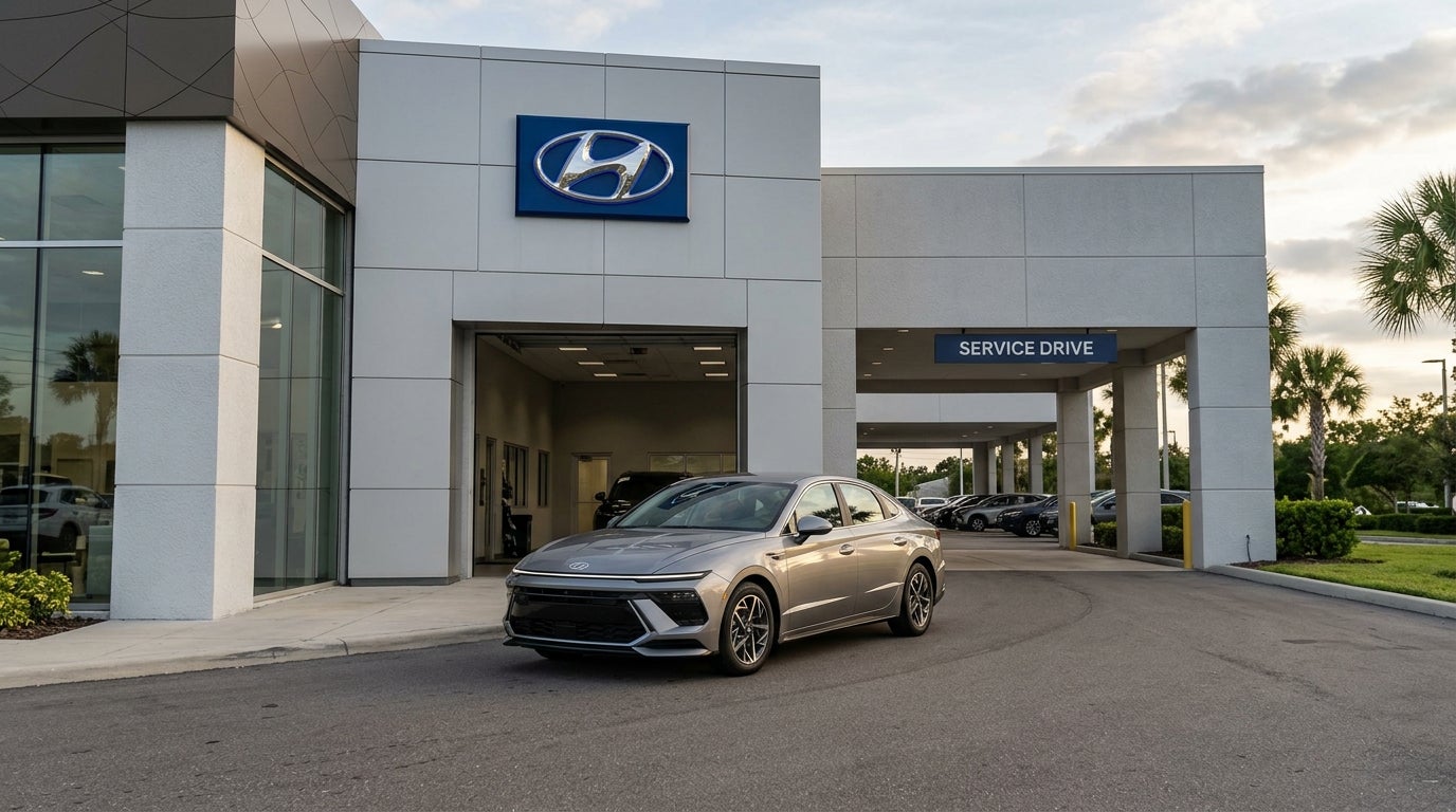 A silver Hyundai Sonata parked in front of a modern Hyundai dealership with a Service Drive canopy. (Representative image for illustration purposes only. Actual vehicle may vary based on trim and configuration.)