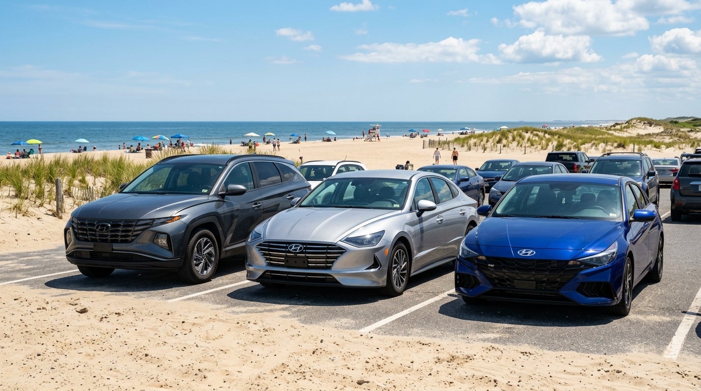 A dark grey SUV, a silver sedan, and a blue sedan parked in a sandy lot next to a sunny beach. (Representative image for illustration purposes only. Actual vehicle may vary based on trim and configuration.)