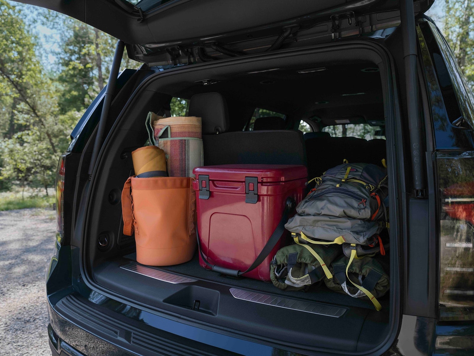 The back of Tahoe Cargo filled with outdoor gear and a cooler.