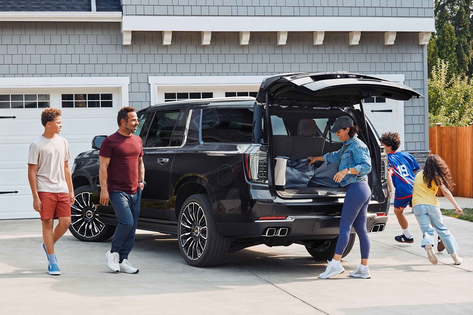 A family loads luggage into the back of a Suburban.