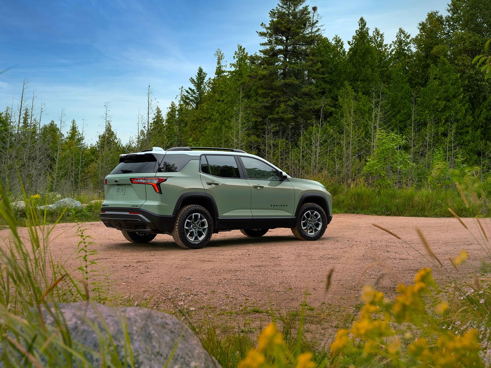 Chevy Equinox parked on a dirt road surrounded by trees and greenery.