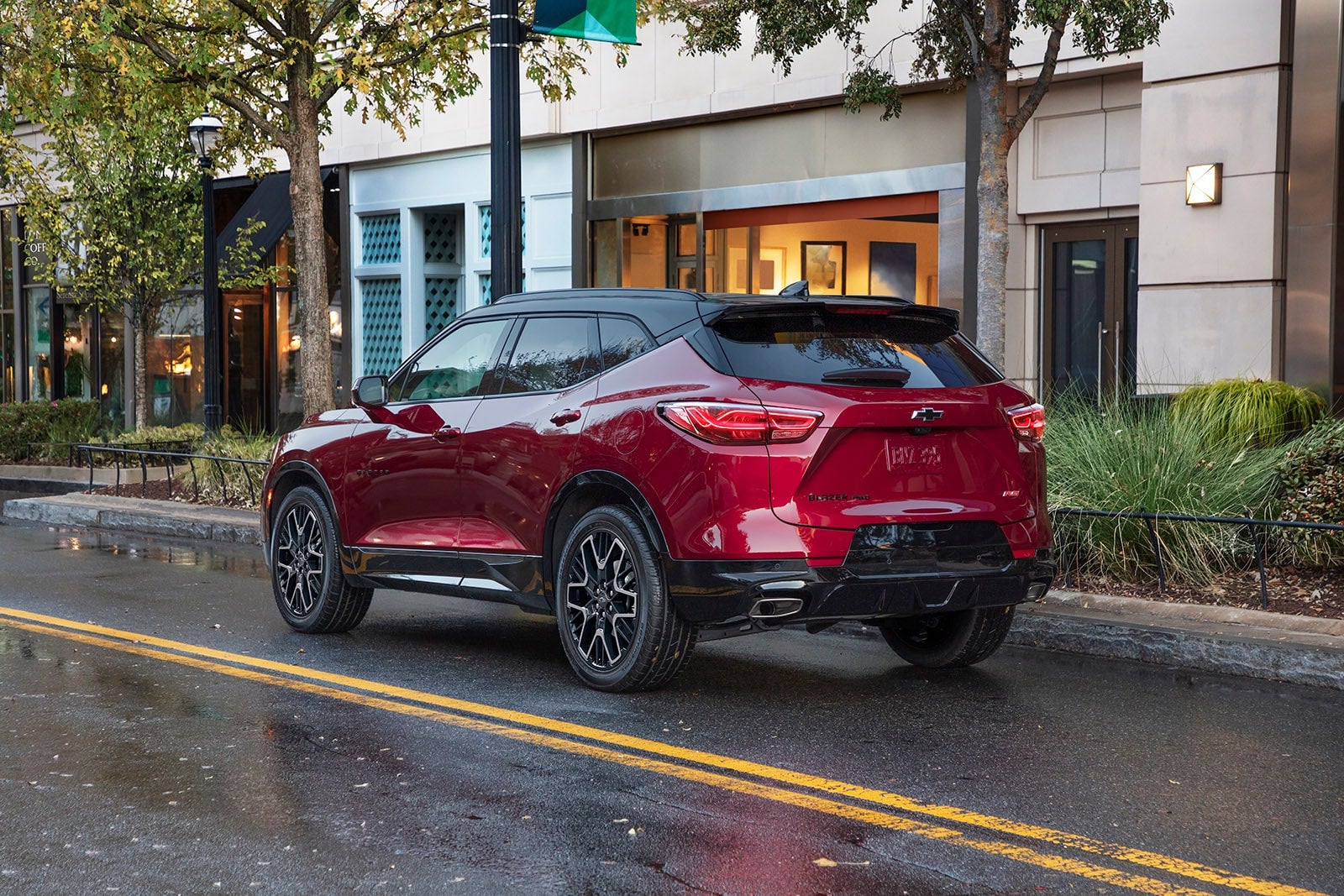 chevy blazer parked next to storefronts and trees.