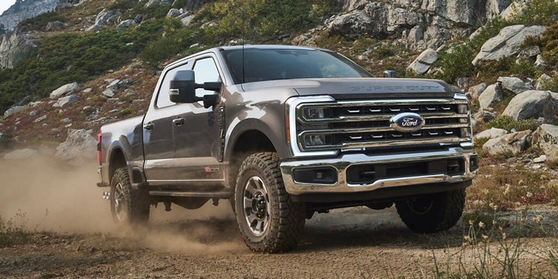 A grey Ford Super Duty pickup truck driving on a dirt path.