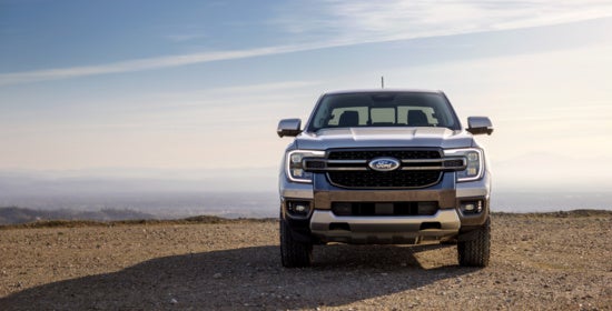 Silver Ford pickup truck parked on rocky terrain with misty mountain landscape in background, showcasing rugged design