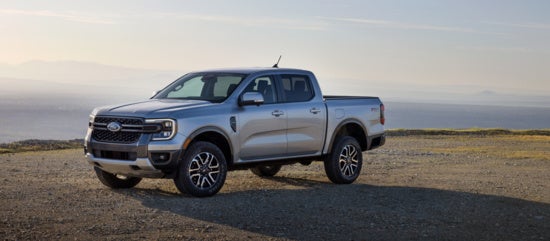 Silver Ford Ranger pickup truck parked on rocky terrain with ocean horizon in background, showcasing rugged design