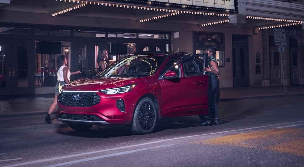 Friends getting into a red 2025 Ford Escape parked under a marquee