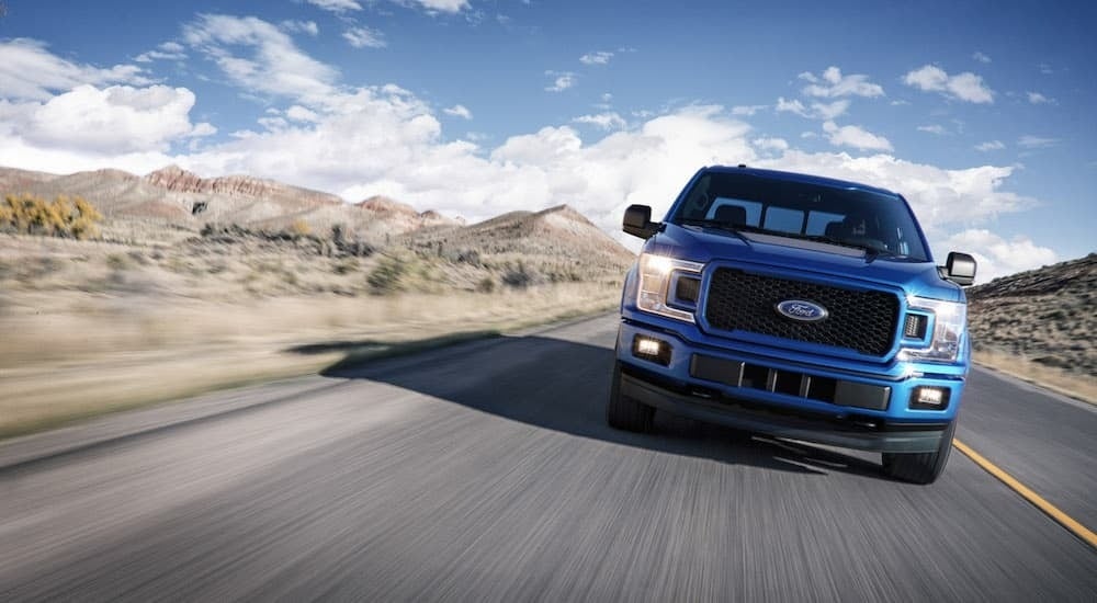 Front view of a used blue 2018 Ford F-150 for sale in Rhinebeck driving down an open road.