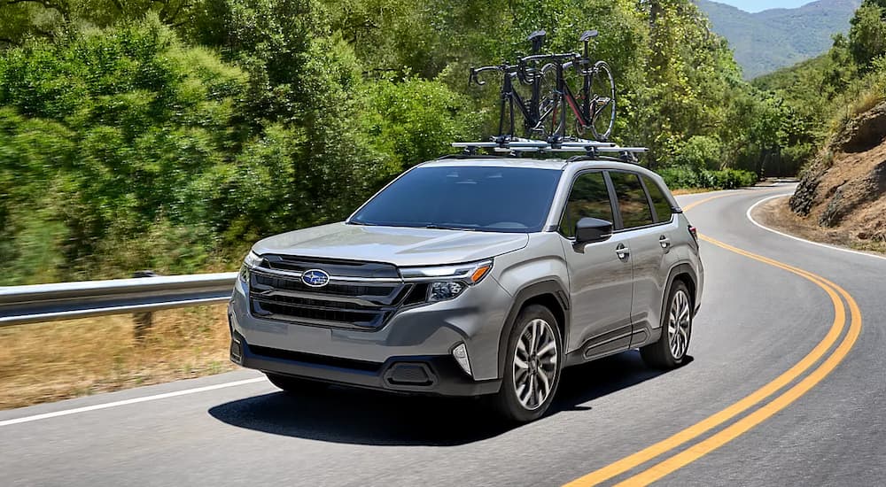 Silver 2025 Subaru Forester driving around a bend.