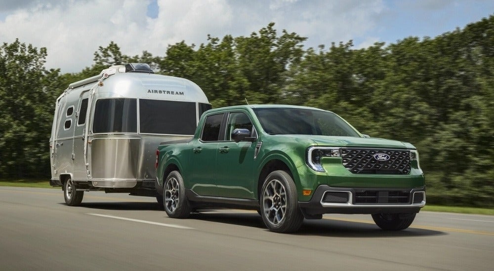 A green 2025 Ford Maverick for sale is shown towing an Airstream