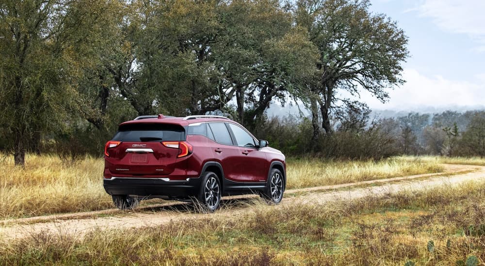 A red 2022 GMC Terrain driving on a dirt road.