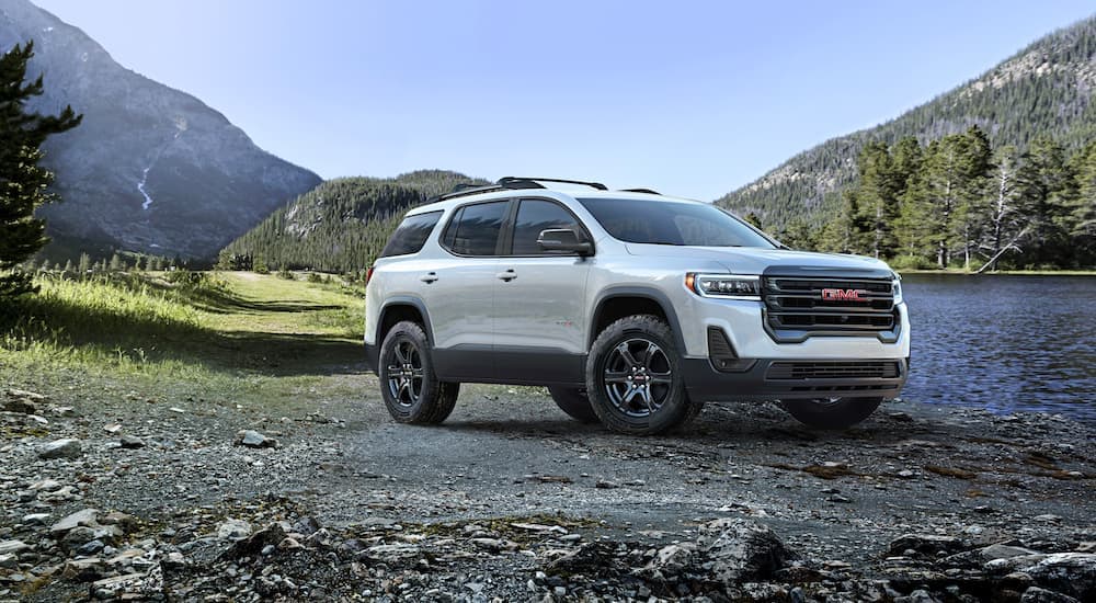 A white 2023 GMC Acadia AT4 parked near a lake.
