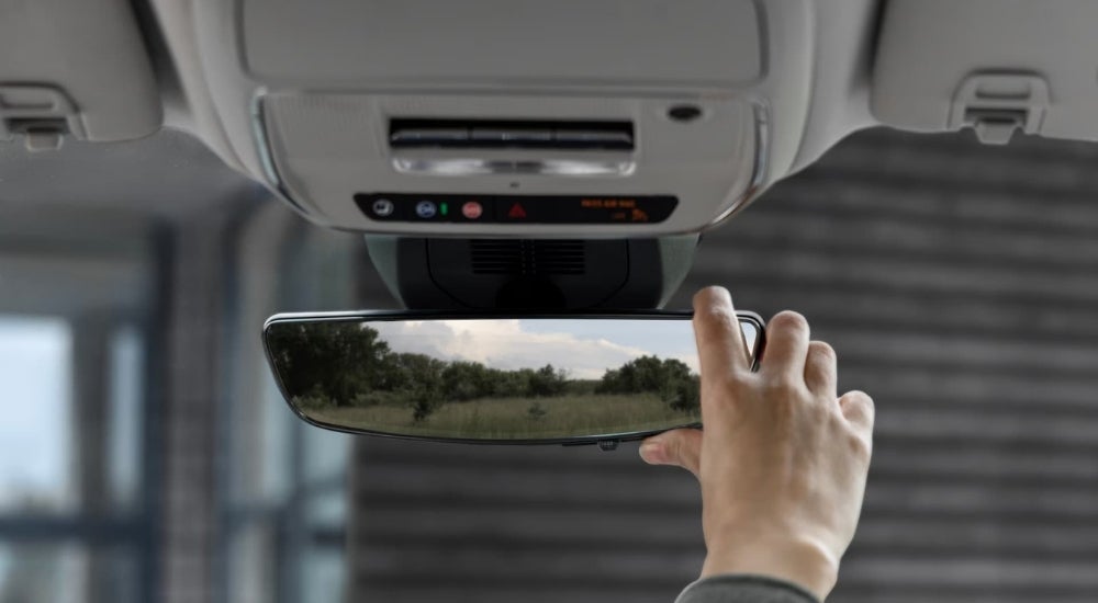 Person adjusting the rear view mirror of a 2025 GMC Terrain