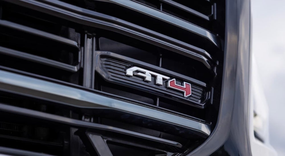 Close-up shows a grille badge on a 2026 GMC Terrain AT4