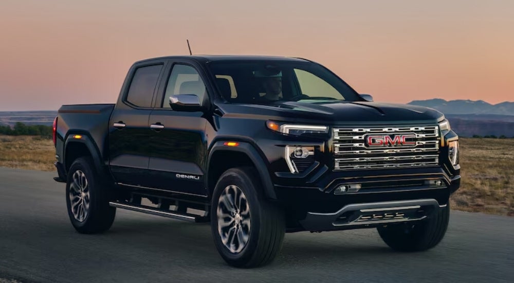 Black 2024 used GMC Canyon for sale driving on a highway