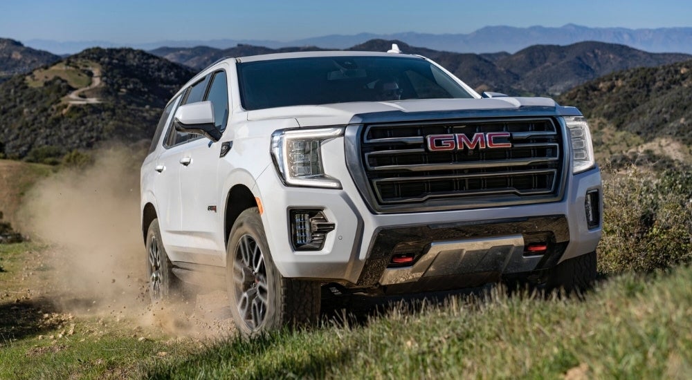 White 2023 GMC Yukon AT4 driving off-road