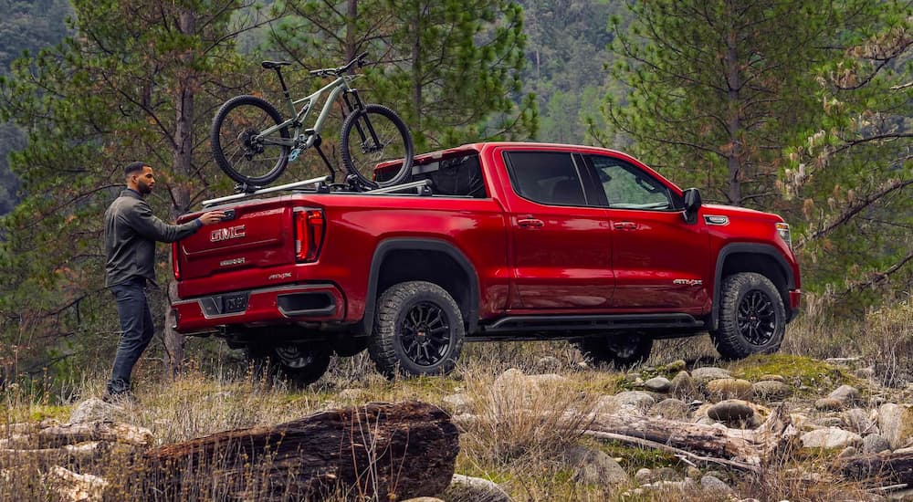 Person loading a bike on a red 2024 GMC Sierra 1500 AT4X after leaving a GMC dealer