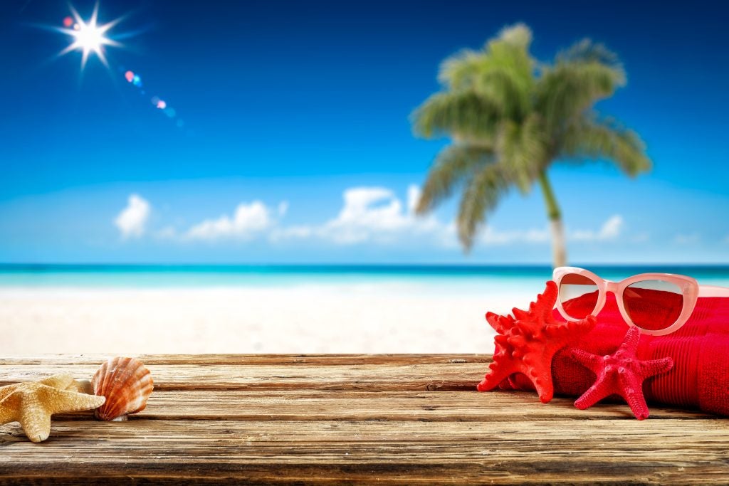 Beach items on table with ocean and palm tree view.