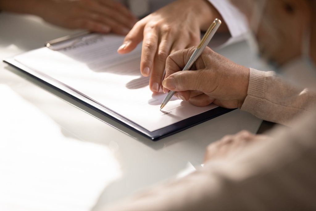 Hand signing alimony law documents during legal process.
